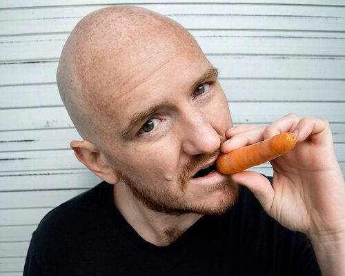 Künstler Norbert Ortner mit einer Karotte als Zigarre im Munde